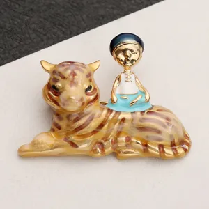 Close-up of a vintage-style golden tiger brooch with a small figure sitting on its back.