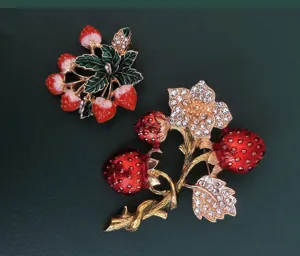 Detaillierte Ansicht von Vintage-Emaille-Broschen mit Erdbeeren und Strasssteinen.