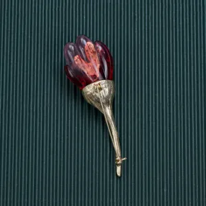 Detailed close-up of a vintage baroque style brooch with a red bud and textured gold stem