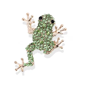 Detail of green rhinestone frog brooch with sparkling crystal eyes and golden finish.