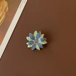 Detailed close-up of a vintage baroque enamel flower brooch with blue and green petals
