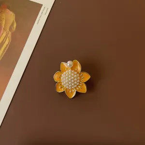 Macro detail of a vintage enamel flower brooch with elegant pearl embellishments