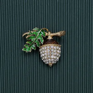 Detailed close-up showing the sparkling rhinestones and green enamel leaf of the acorn brooch