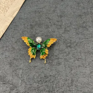 Detailed macro view of a vintage Baroque butterfly brooch with green yellow enamel and pearl