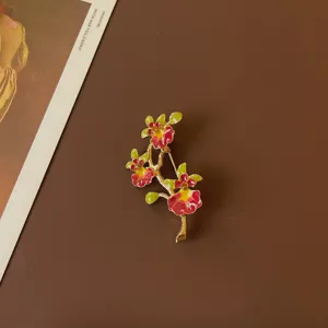 Vintage enamel flower brooch with vibrant red and green petals on brown background
