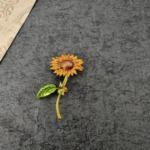 Detailed view of a vintage enamel sunflower brooch with vibrant yellow and green accents