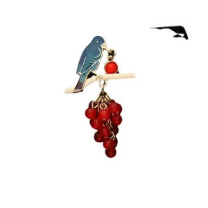 Elegant baroque bird on branch brooch with red bead cluster on a clean white background