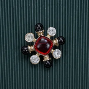 Close-up detail of a vintage Baroque style brooch with a red central stone and black beads