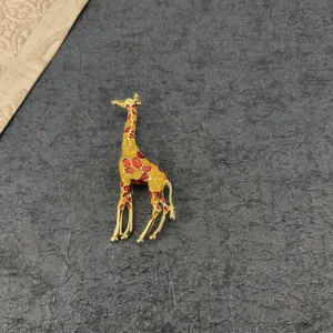 Macro view of vintage enamel giraffe brooch featuring yellow and orange spots on gold base