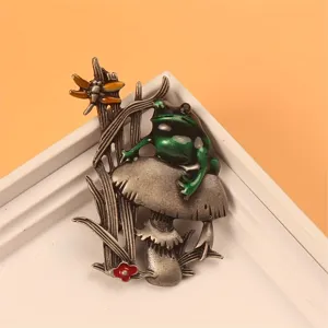 Macro detail of a vintage animal frog on mushroom brooch pin with green enamel finish