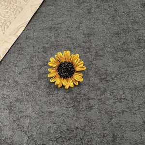 Macro view of vintage yellow enamel sunflower brooch pin on a textured dark background