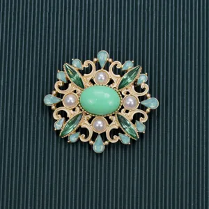 Detailed macro view of a vintage Baroque style brooch with green stones and pearls