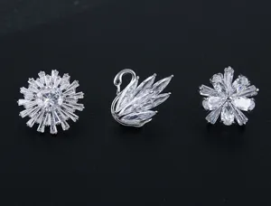 Vista detallada de tres broches de cristal micro-pavé con diseños de cisne y flores.