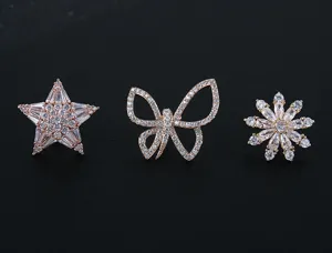 Vista detallada de broches brillantes de estrella, mariposa y flor con circonitas cúbiche