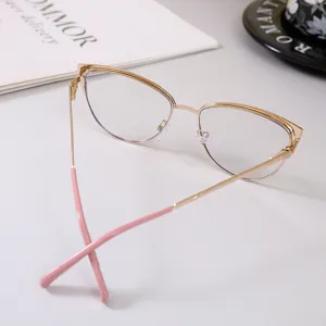 Primer plano de una elegante montura de gafas de ojo de gato en metal dorado con puntas rosas.