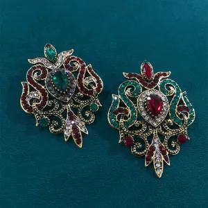Detailansicht von kunstvollen Vintage-Barock-Broschen mit roten und grünen Mittelsteinen