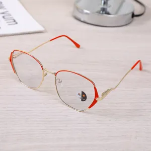 Detail of retro gold-red metal frame glasses with anti-blue light lenses on a desk.