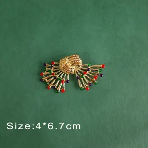 Close-up of a vintage baroque gold brooch with red, green and purple gems, size 4*6.7cm