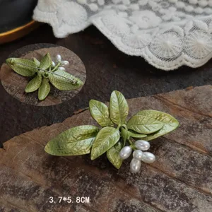 Detail showing the intricate green enamel and white berries of the vintage lily brooch