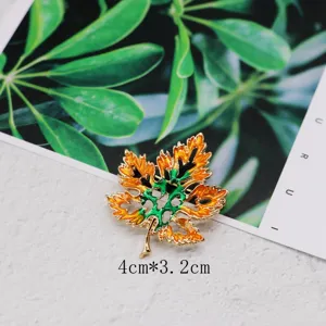 Detailed macro shot of vintage orange and green enamel maple leaf brooch pin, size 4cm by 3.2cm