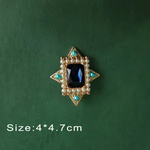 Close-up view of a vintage Baroque style brooch featuring a deep blue gemstone and pearls