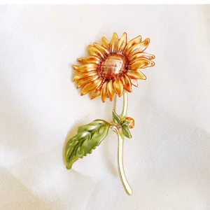 Close-up van geschilderde zonnebloem broche met vintage emaille afwerking op satijn