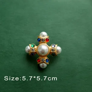 Detailed macro shot of a Baroque gold cross brooch with pearls and gems