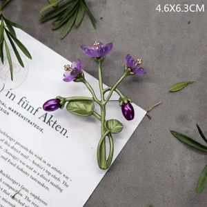 Detailweergave van een vintage bloemenbroche met paarse bloemen en groene stengels
