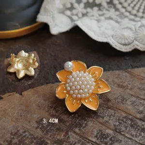 Detailed macro view of a 3.4cm vintage orange enamel flower brooch with white pearls