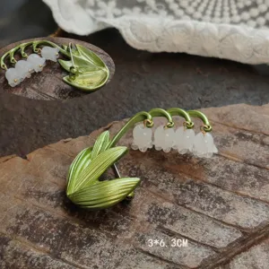 Vintage green lily of the valley brooch with white bell flowers on rustic wood background