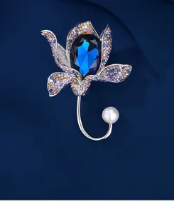 Macro detail of elegant crystal flower brooch featuring a deep blue gemstone and pearl.