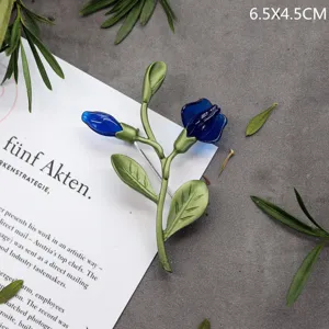 Gedetailleerd beeld van een elegante vintage bloem speld met blauwe bladeren en stelen