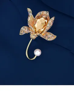 Detailed view of elegant gold flower brooch with amber crystal petals and white pearl