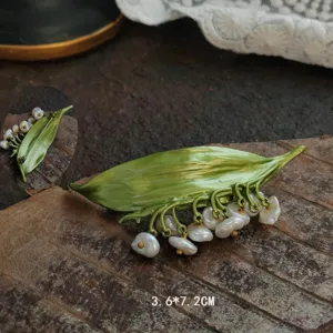 Close-up detail of vintage handmade enamel lily of the valley brooch with pearls