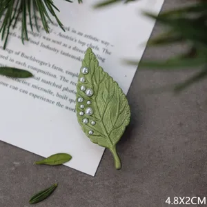 Gedetailleerde macro-opname van een elegante groene bladbroche met parelaccenten