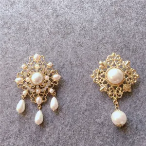 Detailed macro view of two vintage gold-tone brooches with elegant white faux pearls.