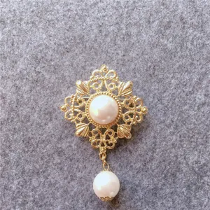 Detailed view of a vintage gold-tone brooch with elegant pearl accents on grey felt.