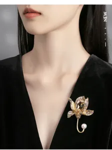 Close-up of elegant crystal flower brooch with pearl on a black velvet dress