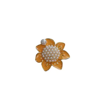 Vintage orange enamel flower brooch with white pearl cluster centerpiece on white background