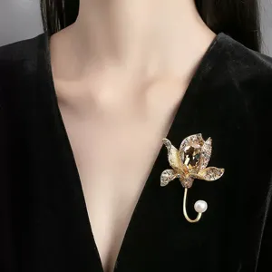 Elegant golden flower brooch with amber crystal and pearl detail on black velvet