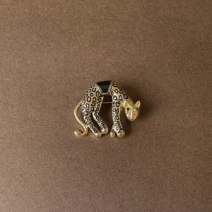 Detailed view of a vintage gold-toned leopard brooch with black enamel spots and green eyes