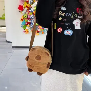 Détail d'un sac à bandoulière en peluche Capybara porté par un mannequin en intérieur.