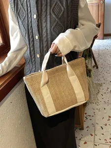Primer plano de un bolso tipo capazo de paja natural con asas de lona en color blanco.