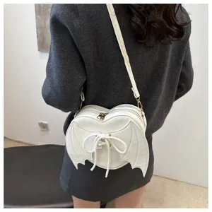 Creatieve witte hartvormige crossbodytas met vleermuisvleugels en strik op model