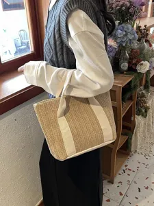 Bolso tote de paja tejido a mano con correas de lona llevado por mujer en café