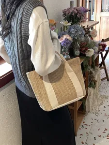 Detalle de bolso de paja trenzada con asas de lona blanca en un ambiente de cafetería.