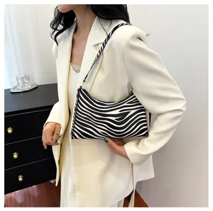Close-up detail of a zebra print underarm bag held by a model in a white blazer