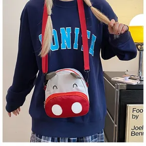Detailansicht einer süßen rot-weißen Cartoon-Kuh-Umhängetasche, getragen mit einem Sweatshirt