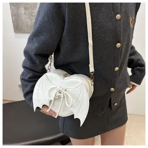 Witte hartvormige crossbodytas met duivelsvleugelontwerp gedragen door model