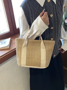 Primer plano de un bolso de paja tejida rústico sostenido por una modelo casual.
